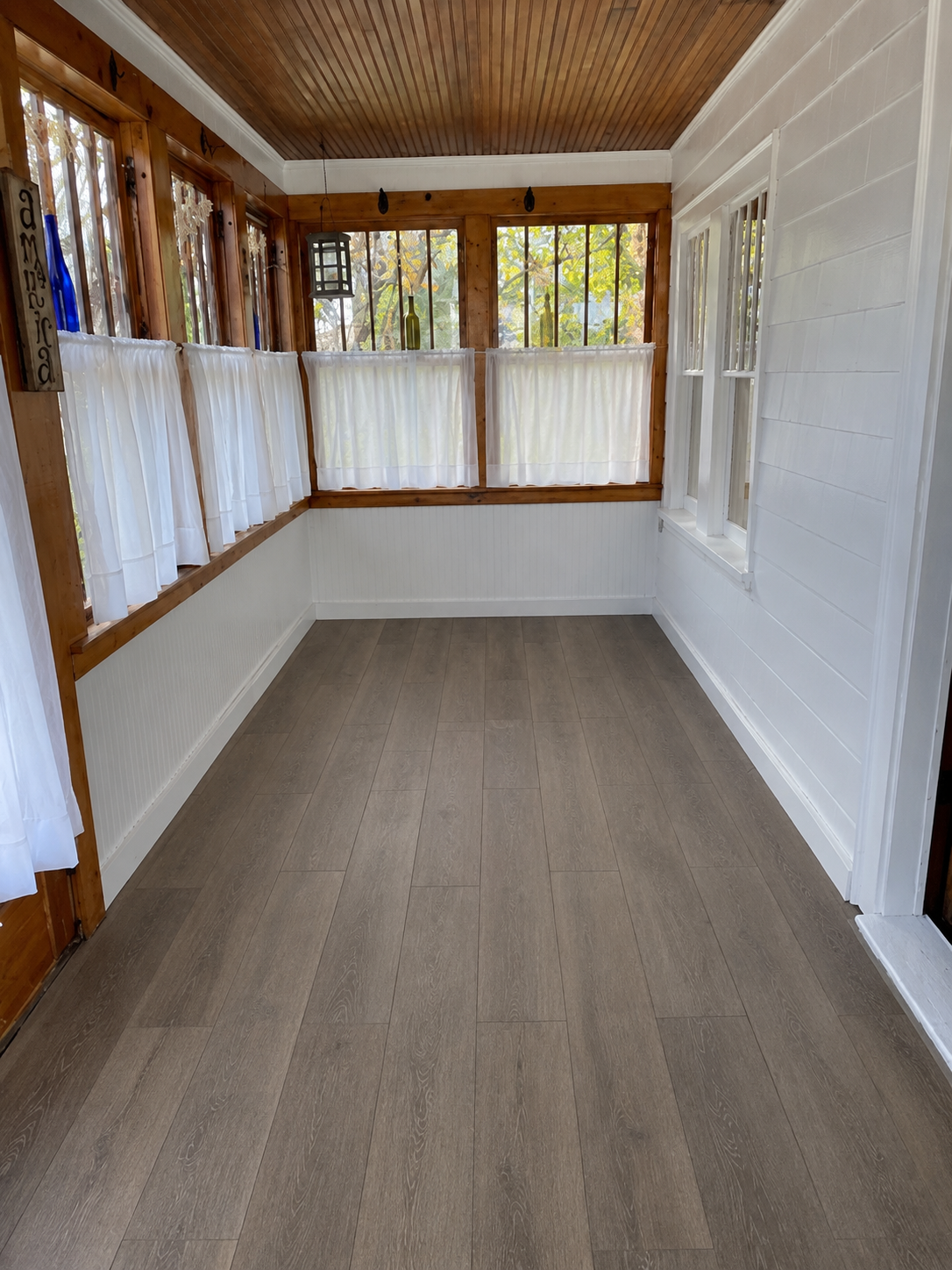 Porch after renovation — fresh white walls and new wood-look flooring